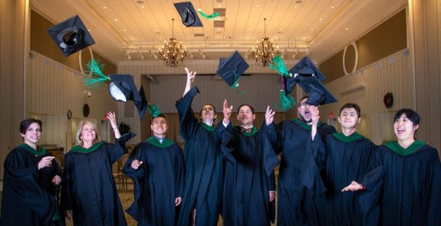 Graduates throw their caps up into the air.