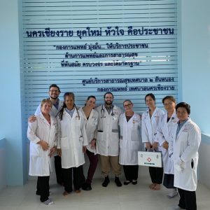 Students and staff pose in front of a sign.