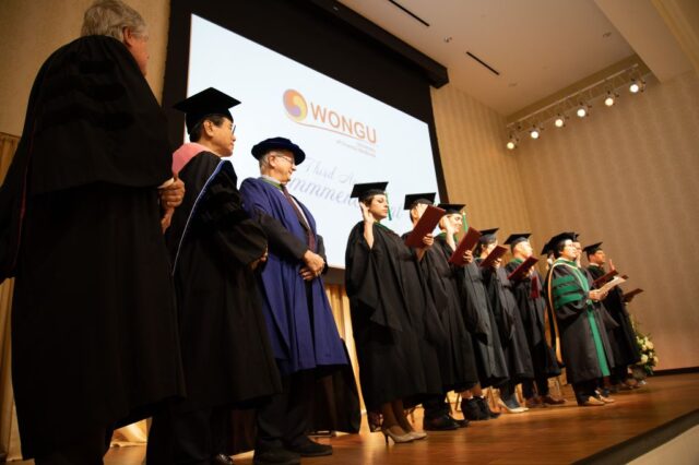 The graduates recite their oath with their right hands raised as the speakers look on.