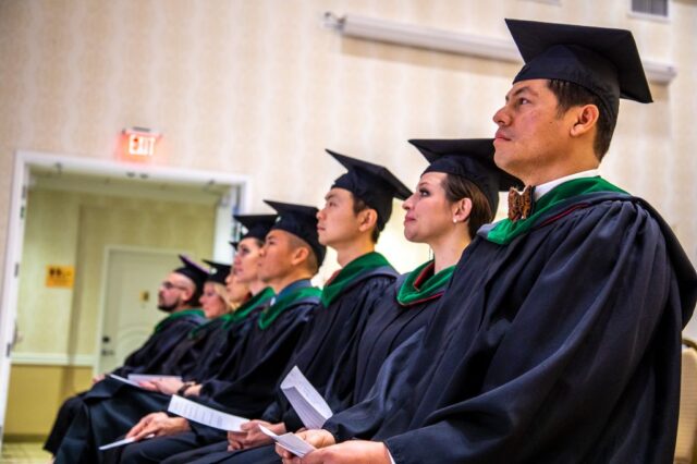The graduates sit in the first row facing towards the stage.